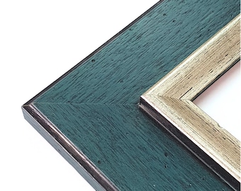 May include: Close-up of the corner of a picture frame with a teal green outer frame and a silver inner frame.