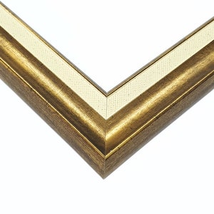 May include: A gold picture frame with a white mat. The frame has a decorative, ornate design.
