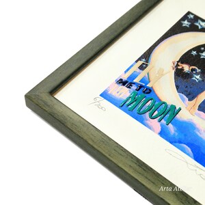 May include: A framed print of a woman sitting on a crescent moon with the text "Fly Me To The Moon" in green letters. The print is signed and numbered 6/20.