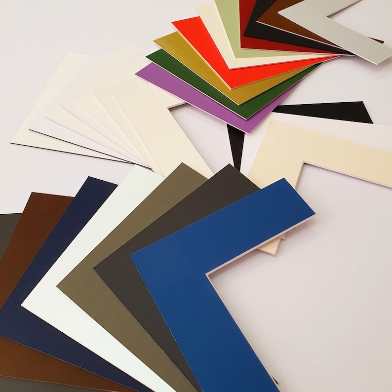 May include: Assortment of colored mat boards in various shades of white, brown, green, blue, red, and purple. The mat boards are arranged in a fan shape, with the corners of each board visible.