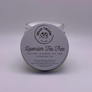May include: A white jar with a black and white label that says "Hello Tallow Est. 2023" and "Lavender Tea Tree Tallow, Lavender Tea Tree Essential Oil". The label also includes directions for use.