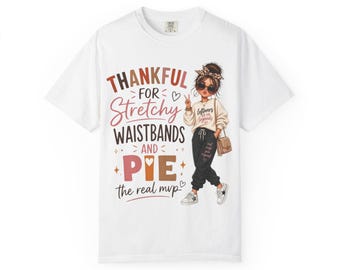 May include: A white t-shirt featuring a graphic illustration of a person wearing a leopard print headband, sunglasses, a beige sweatshirt, and black joggers. The text reads: THANKFUL FOR Stretchy WAISTBANDS AND PIE the real mvp.