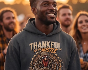 May include: A charcoal gray hooded sweatshirt featuring a graphic print of a turkey wearing a beanie and sunglasses, with the text "THANKFUL FOR THE HUSTLE" and "BLESSED FOR THE FEAST" alongside illustrations of pumpkins and corn stalks.
