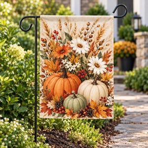 Peut inclure: Un drapeau de jardin rectangulaire présentant un arrangement automnal saisonnier. Le motif affiche une grosse citrouille orange, une citrouille blanche et une plus petite citrouille verte entourées de feuillage d'automne, de blé, de pommes de pin et de marguerites blanches.