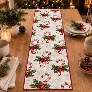 May include: A rectangular quilted table runner featuring a repeating pattern of red and white candy canes, green holly leaves, and red berries on a white background with a subtle snowflake print and a solid red fabric border trim.