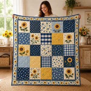 Puede incluir: Una colcha de patchwork con una cuadrícula de cuadrados alternos con estampados de girasoles, patrones de cuadros vichy azules y blancos, y motivos florales pequeños. La colcha tiene un borde azul oscuro con un patrón de girasoles.