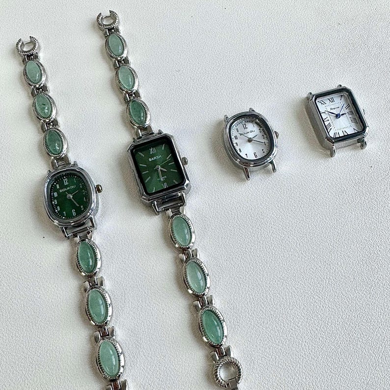 May include: Silver-toned watches with green faces and oval-shaped green stone accents. Two watches have matching stone bracelets. One watch has a white face with black numerals, and another has a green face with black numerals. The watches have a vintage aesthetic.