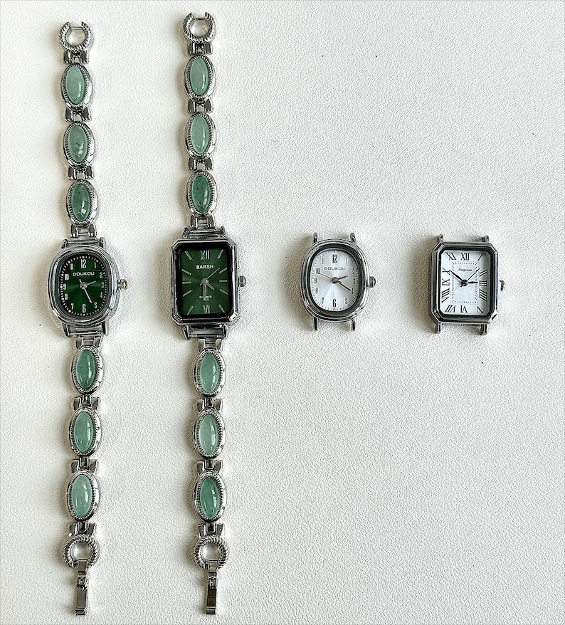 May include: Four watches with silver-toned metal cases. Two have green watch faces and matching green stone bands. The other two have white watch faces. One has a rectangular face with Roman numerals, and the other has an oval face with Arabic numerals.
