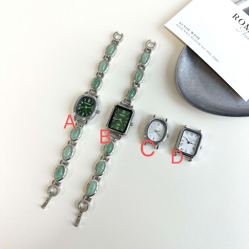 May include: Four women's watches. Two have green watch faces and matching green stone bracelets. The other two watches have silver cases and white watch faces. One has Roman numerals, and the other has Arabic numerals.