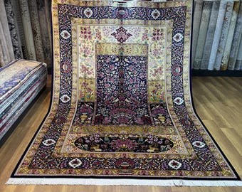 May include: A large, rectangular Persian rug with a navy blue border and a central floral design in shades of pink, yellow, and green. The rug has a cream-colored fringe and is displayed in a carpet store.