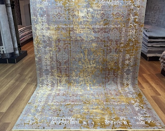 Könnte beinhalten: Ein großer, rechteckiger Teppich mit einem verblassten, abgenutzten Muster in Gold-, Blau- und Rottönen. Der Teppich hat einen Vintage-Look und ist aus einem weichen, plüschigen Material gefertigt.