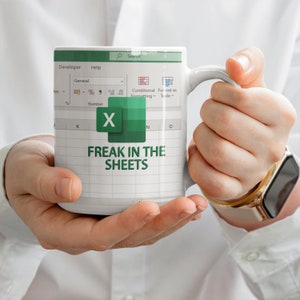 May include: White coffee mug with a green Excel spreadsheet design. The mug has the text "FREAK IN THE SHEETS" on it.