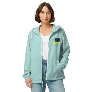 May include: A light blue hooded windbreaker jacket with a zipper closure. The jacket has a black and white American flag with a yellow stripe on the left chest.