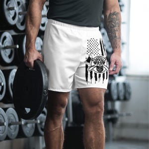 May include: White athletic shorts with a black and white American flag design and a skull with crossed axes graphic.