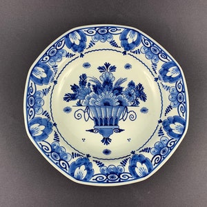 May include: A white ceramic plate with a blue and white floral design. The plate has an octagonal shape and features a central floral motif in a basket.