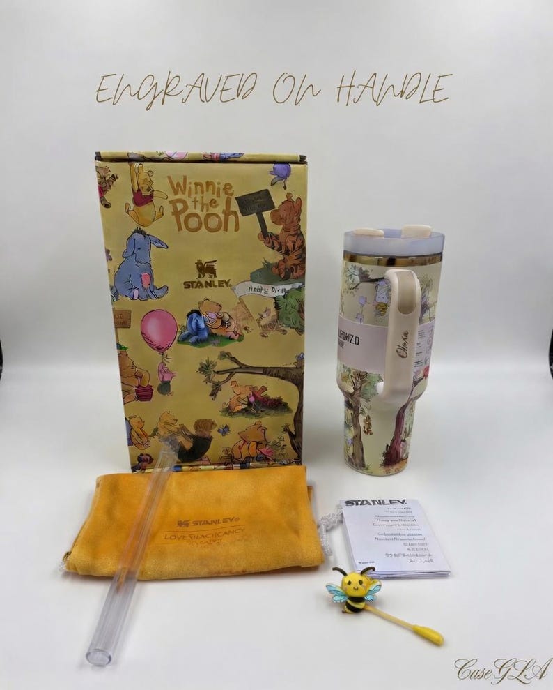 May include: A Winnie the Pooh themed gift set featuring a tumbler, box, straw, and accessories. The tumbler and box have illustrations of Pooh and friends. The set includes a yellow pouch and a bee-shaped charm.