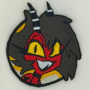 May include: Embroidered patch featuring a cartoon character with red and yellow features, black hair, and white horns. The character is smiling with a mischievous expression.