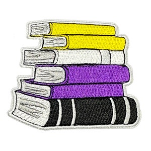 May include: A stack of embroidered books in a purple, white and yellow colour scheme. The books are stacked on top of each other, with the largest book at the bottom and the smallest book at the top.