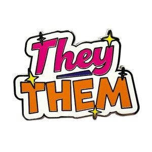 May include: A white enamel pin with the words "They Them" in a retro style font. The word "They" is in pink and the word "Them" is in orange. There are yellow stars around the words.