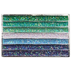 May include: A rectangular pin with a silver border, featuring horizontal stripes of glitter in shades of green, blue, and purple. The pin has a shiny, reflective surface, and the glitter adds a sparkling effect. The design is a flag.
