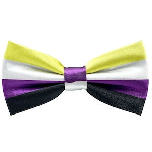 Pode incluir: Uma gravata borboleta amarela, branca, roxa e preta com acabamento em cetim.