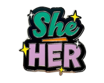May include: A black enamel pin with the words "She Her" in a colorful, stylized font. The letters are outlined in black and filled with green, orange, and purple. There are yellow stars around the letters.