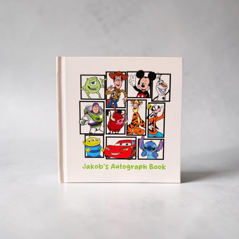 May include: A cream-colored autograph book featuring a grid of cartoon characters, including Mike Wazowski, Woody, Mickey Mouse, and Stitch. The book is labeled "Jakob's Autograph Book" in green text.
