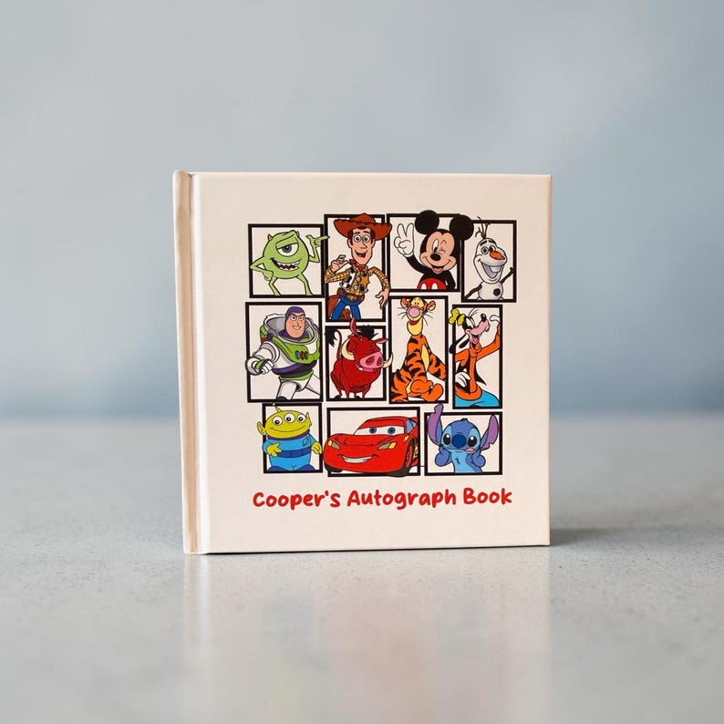 May include: A cream-colored autograph book featuring a collage of Disney characters, including Mickey Mouse, Buzz Lightyear, and Lightning McQueen. The title "Cooper's Autograph Book" is printed in red script.