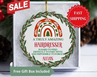 May include: A Christmas ornament with a green wreath and a rainbow design. The ornament says "A truly amazing hairdresser is hard to find, difficult to part with and impossible to forget." The name Alexis is written below the text.