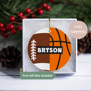 May include: A round, white ceramic ornament with a half brown football and half orange basketball design. The name "BRYSON" is printed in white letters on the ornament.