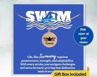 May include: A blue gift box with a gold necklace featuring a swimmer pendant. The pendant has the word "Emma" engraved on it. The box has the text "SWIM" and "Life, like Swimming requires perseverance, strength, and adaptability. With every stroke, you navigate challenges and move forward, proving that dedication leads to success." The box also has a yellow sticker that says "Gift Box Included".