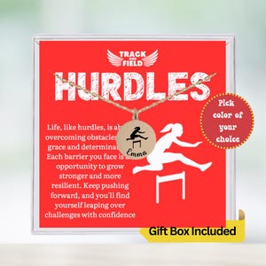May include: A red gift box with a white border and a gold necklace with a silver pendant featuring a silhouette of a person jumping over a hurdle. The pendant has the word "Emma" engraved on it. The box has the words "Track and Field" and "Hurdles" printed on it. The text "Pick color of your choice" is printed on a circle sticker on the box. The text "Gift Box Included" is printed on a yellow sticker on the box.