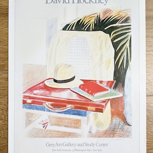 Op de afbeelding: Een tentoonstellingsposter van David Hockney voor het Grey Art Gallery and Study Center, gedateerd 3 april tot 3 mei 1980. De illustratie toont een rode koffer, een strooien hoed en een rood boek op een stoel, met palmbladeren op de achtergrond.