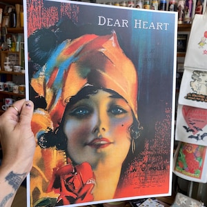 May include: A vintage print titled "Dear Heart" featuring a woman with blue eyes and a red rose. The print has text including "W.C. Polla" and "C.C. Church & Co.". The woman is wearing a colorful headscarf.
