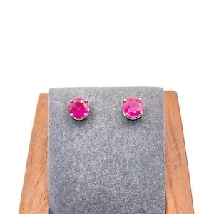 Peut inclure: Une paire de boucles d'oreilles en argent avec des pierres rondes de couleur rose vif.