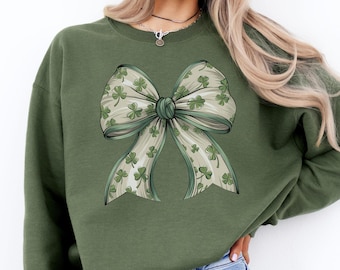 May include: A green sweatshirt with a large white bow printed on the front. The bow is decorated with shamrock patterns.