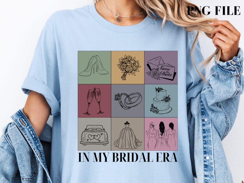 以下が含まれることがあります： 薄い青色のTシャツに、9つの正方形のグリッドで構成されたグラフィックデザインが施されています。各正方形には、靴、シャンパンフルート、花束、ウェディングケーキ、指輪、車、ウェディングドレス、2人のブライズメイドなど、結婚式に関連するさまざまなイラストが描かれています。グリッドの下には「In My Bridal Era」というテキストが印刷されています。