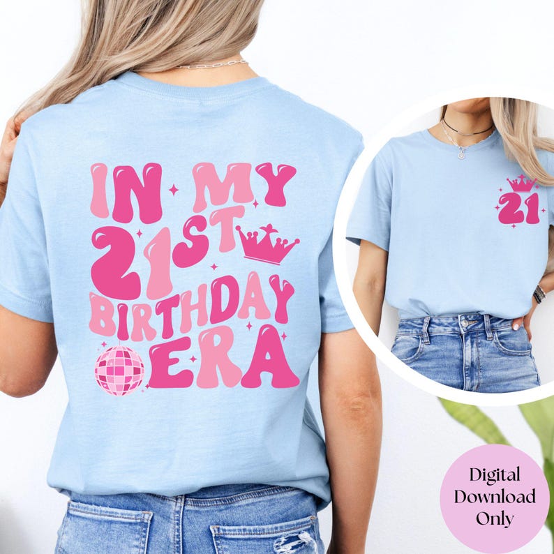 May include: A light blue t-shirt with the text "In My 21st Birthday Era" in pink with a crown and disco ball graphic. The shirt is shown on a model wearing blue jeans.
