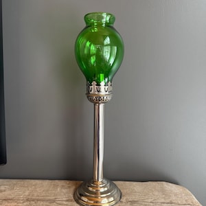 May include: A vintage green glass candle holder with a silver-coloured metal base and stem. The glass top is a vibrant green, and the base is round. The candle holder stands approximately 30 cm tall.