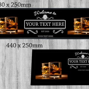 Könnte beinhalten: Schwarze Barmatte mit dem Text "Welcome to YOUR TEXT HERE EST 2020 YOUR TEXT HERE" und zwei Gläsern mit bernsteinfarbener Flüssigkeit. Die Barmatte ist in zwei Größen erhältlich: 880 x 250 mm und 440 x 250 mm.