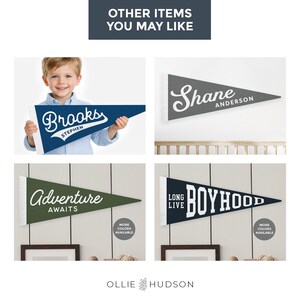 Op de afbeelding: Een verzameling gepersonaliseerde wimpelvaantjes in verschillende kleuren. E&eacute;n vlag wordt door een kind vastgehouden. De vlaggen tonen namen en zinnen als "Brooks", "Shane", "Adventure Awaits" en "Long Live Boyhood". De vlaggen hebben een witte rand.