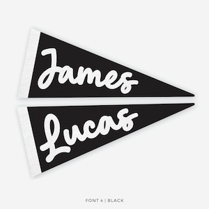 Op de afbeelding: Twee zwarte wimpels met witte tekst 'James' en 'Lucas' in een sierlijk lettertype. De wimpels hebben een witte rand aan de linkerkant. De tekst 'FONT 4 | BLACK' staat onderaan.