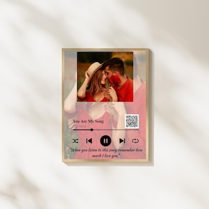 Puede incluir: Impresión enmarcada en madera con una foto de una pareja. El diseño incluye una interfaz de reproductor de música con el texto "You Are My Song" y un código QR. La cita de abajo dice: "When you listen to this song, remember how much I love you."