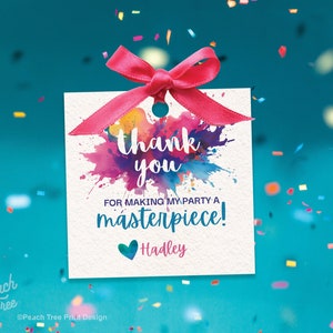 Pu&ograve; includere: Un'etichetta di ringraziamento bianca con un nastro rosa e un design ad acquerello colorato. Il testo recita "Grazie per aver reso la mia festa un capolavoro!" con il nome "Hadley" sotto.