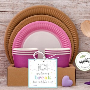 May include: A printable gift tag with a blue background and colorful text that says "You deserve a break, dinner and dishes on us!"  The tag is tied with twine and placed on a brown cardboard box with pink and brown paper plates and cups.