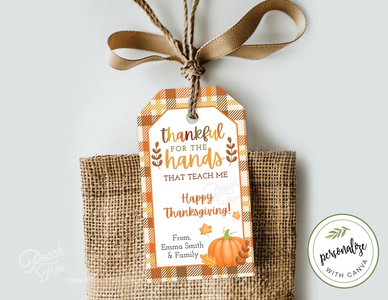 Op de afbeelding: Thanksgiving cadeaulabel met een geruite rand en de tekst "dankbaar voor de handen die me leren". Een pompoenillustratie en de woorden "Happy Thanksgiving" zijn ook te zien. Het label is met een bruin lint aan een jute zak gebonden.