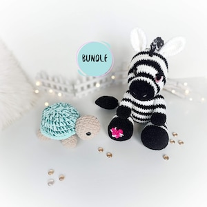 Può includere: Un giocattolo di peluche di zebra lavorato a uncinetto con strisce bianche e nere e un cuore rosa su un piede. Un giocattolo di peluche di tartaruga lavorato a uncinetto con un guscio turchese e un corpo beige è anche nell'immagine. L'immagine ha la parola "BUNDLE" scritta in un cerchio.