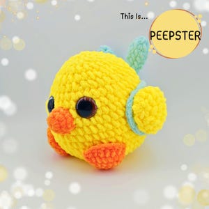 Può includere: Un pulcino giallo all'uncinetto fatto a mano con becco e zampe arancioni e dettagli blu. Il pulcino ha grandi occhi scuri ed è etichettato "PEEPSTER" in un cerchio giallo. Un giocattolo morbido e carino.