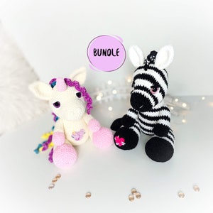 Può includere: Un unicorno bianco all'uncinetto con una criniera rosa e un corno viola si siede accanto a una zebra all'uncinetto bianco e nero con occhi rosa. La parola "BUNDLE" è scritta in un cerchio viola sopra i giocattoli.
