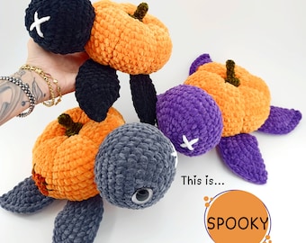 May include: Three crocheted pumpkin-shaped turtle toys. One is black, one is purple, and one is orange. The orange turtle has a white cross on its shell. The text "This is... SPOOKY" is written below the turtles.